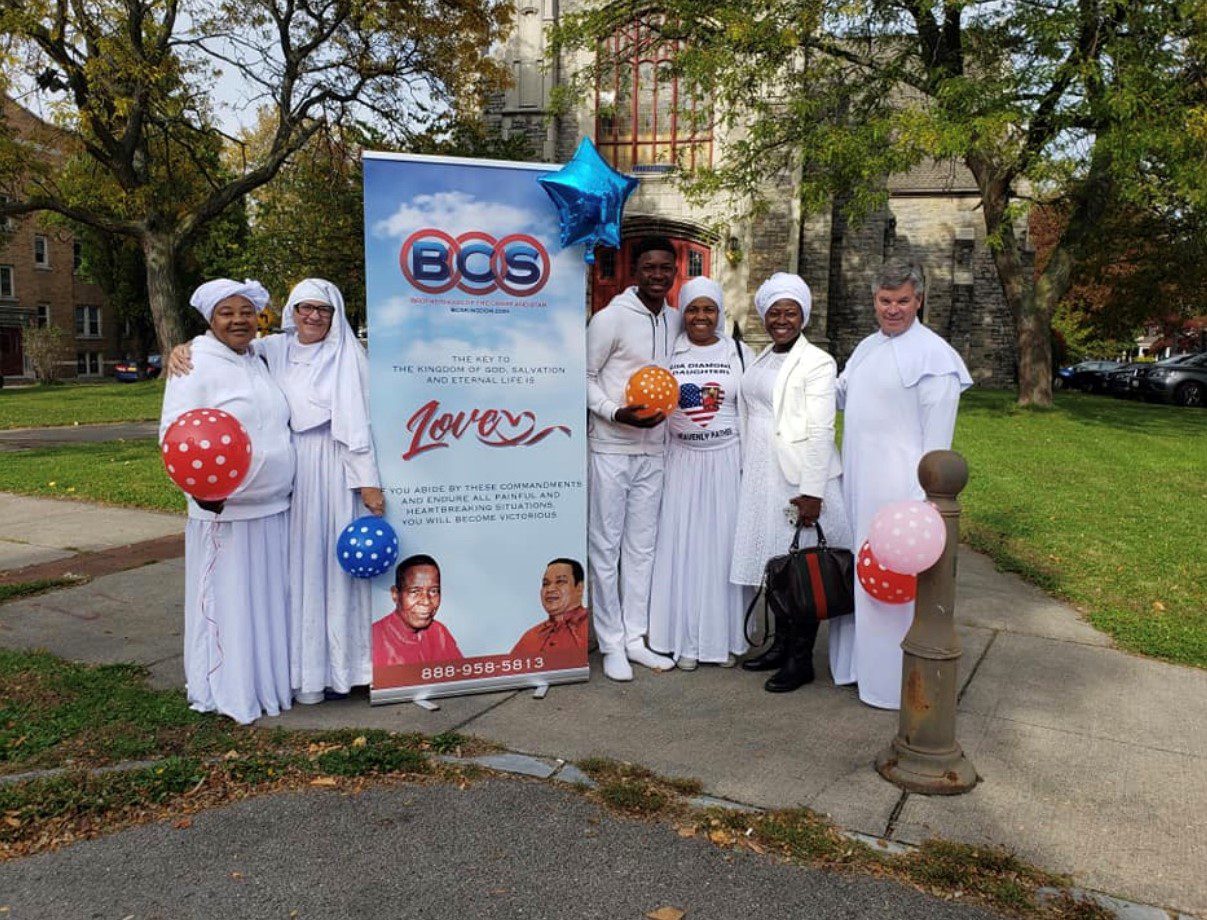 Group in white robes holding balloons outdoors
